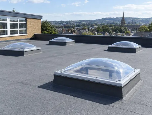 Clear polycarbonate dome rooflights on the flat roof of a school building