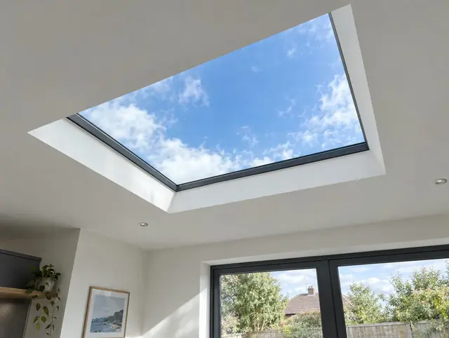 Fixed flat rooflight in the plastered ceiling of a rear extension with blue sky above
