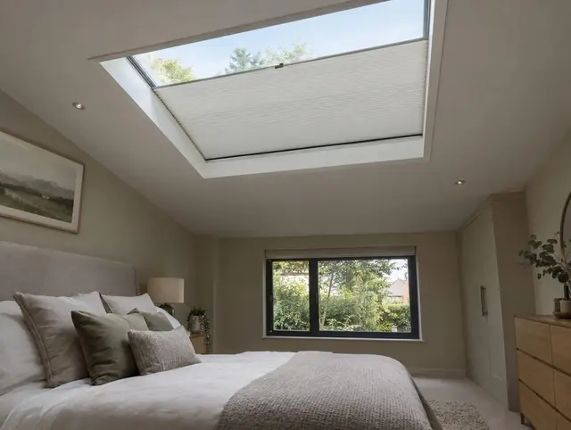 Flat rooflight in a bedroom with an electric pleated blind half closed