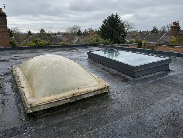 Old yellowed dome rooflight beside a new glass flat rooflight on a flat roof