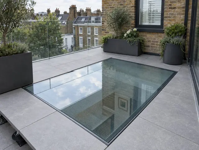 Walk-on glass rooflight set flush into a roof terrace with porcelain paving